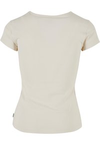 T-shirt beige à manches courtes ajusté avec col rond, vu de dos, design uni avec une petite étiquette en tissu sur la couture latérale.