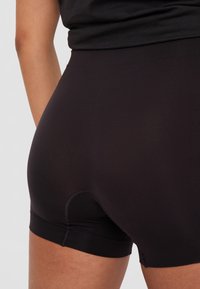 Svart sömlös kort underkläder med en slät yta och en skräddarsydd design, med låg midja och utan synliga sömmar.