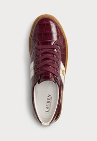 Μαρούλια δερμάτινα αθλητικά παπούτσια με υφή από κροκόδειλο, λευκές ρίγες και καφέ καουτσούκ σόλα. Διαθέτουν στρογγυλή μύτη και κορδόνια.