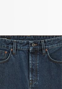 Jeans in denim blu scuro con un classico design a cinque tasche, cuciture visibili e chiusura con bottone in vita.