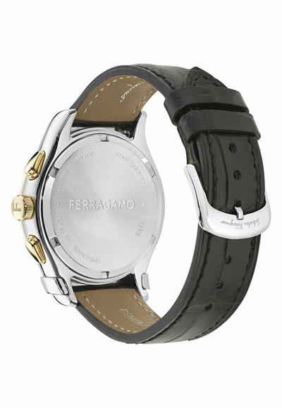 Zadná strana hodinky Ferragamo s puzdrom z nehrdzavejúcej ocele, korunou a tlačidlami v zlatom tóne a čiernym koženým remienkom s prešitými okrajmi.