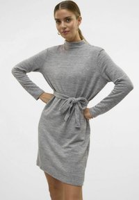 Grijze gebreide jurk met een hoge kraag, lange mouwen en een gestrikt taille detail. Zachte textuur met een ontspannen pasvorm en een zijsplit.