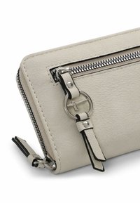 Portefeuille en cuir crème avec des accents noirs, doté d'une fermeture éclair en argent et de quincaillerie décorative, forme rectangulaire fine et surface texturée.