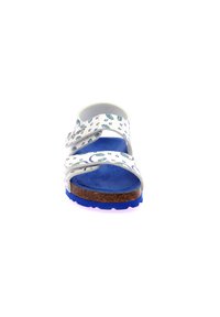 Sandal con la punta abierta blanca y suela azul. Presenta tiras decoradas con patrones verdes y azules. La plantilla de corcho proporciona comodidad y soporte.
