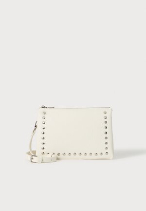 Bolso de mano blanco de cuero con tachuelas plateadas en los bordes, cierre de cremallera y una correa desmontable, con una superficie texturizada.
