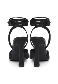 Sandali neri con tacco alto visti da dietro, con cinturini alla caviglia e tacchi a blocco, con il nome del marchio "CALLIOPE" sulle solette.