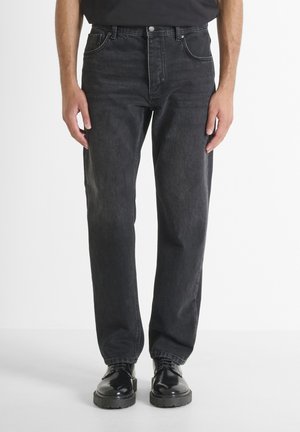 Jean en denim noir avec une coupe décontractée, comportant cinq poches, des coutures contrastées et une fermeture éclair. Équilibre entre confort et durabilité.
