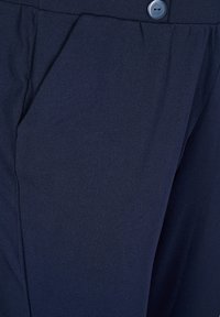 Pantaloni in tessuto blu navy con una texture liscia, dotati di tasche frontali e dettaglio con bottone in vita.