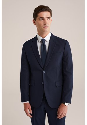 Navy colbert met gestructureerd ontwerp, twee knopen en notch-revers. Vergezeld van een witte dress shirt en een bijpassende stropdas.