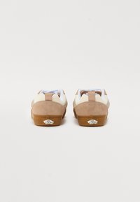 Baskets en daim marron et crème avec une semelle en caoutchouc naturel. Comprend un collier rembourré, un accent de logo sur le talon et une boucle à l'arrière.