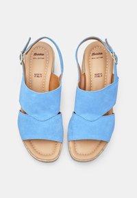 Sandali in suede blu con strappi incrociati, punta aperta e cinturino alla caviglia. Presentano una soletta in pelle color pelle e dettagli di cucitura. Fabbricati in Italia.