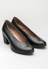 Zapatos de tacón alto de cuero negro con puntera redondeada y tacón cuadrado. Textura suave con un brillo sutil. Forro interior en tonos neutros.
