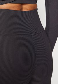 Mørkegrå ribbede leggings med høj talje og tekstureret stof, designet til komfort og fleksibilitet.