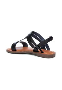 Sandalo in pelle nera con suola piatta in gomma, caratterizzato da cinghie incrociate e una soletta imbottita. Le cuciture marroni a contrasto accentuano il design.