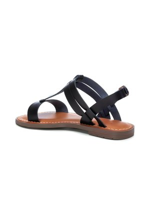Sandalo in pelle nera con suola piatta in gomma, caratterizzato da cinghie incrociate e una soletta imbottita. Le cuciture marroni a contrasto accentuano il design.