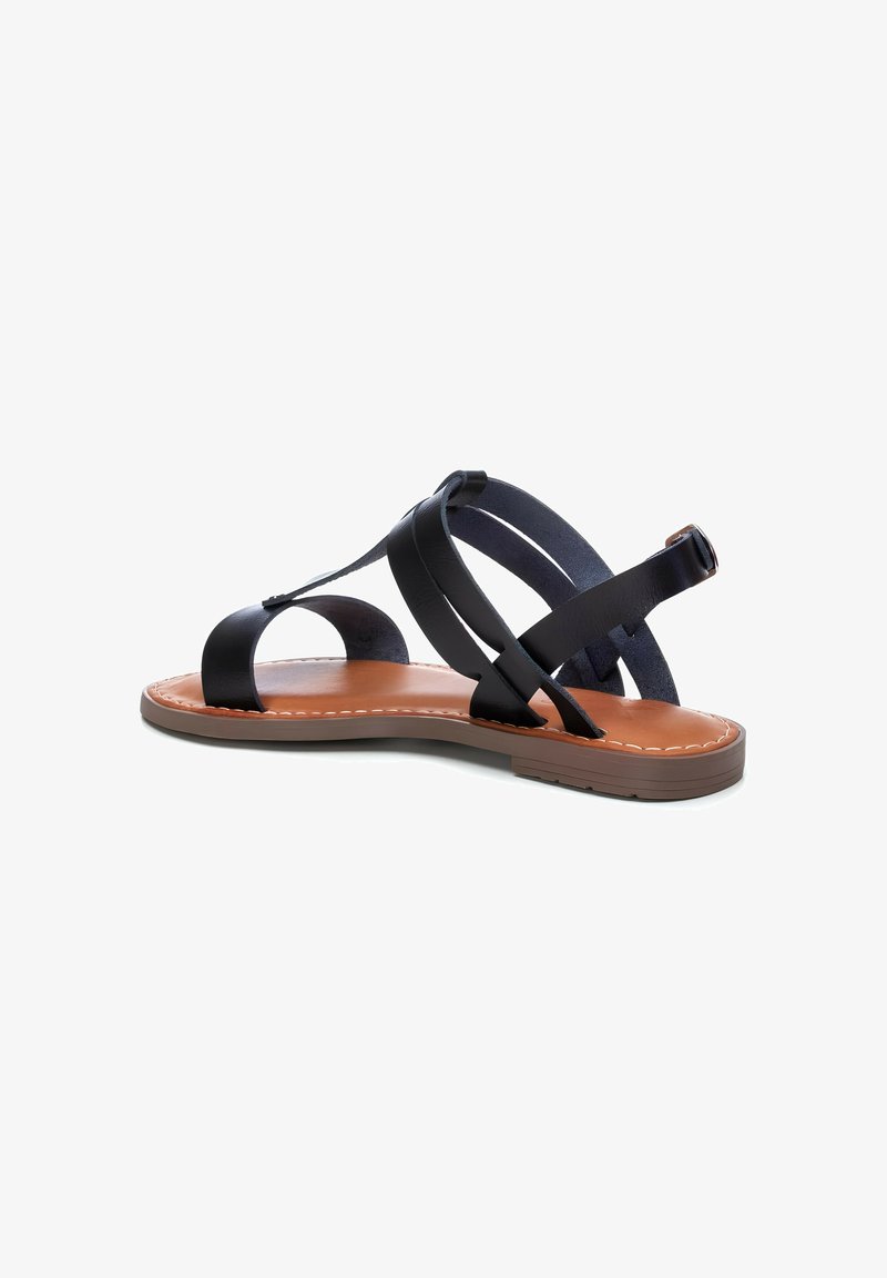 Sandalo in pelle nera con suola piatta in gomma, caratterizzato da cinghie incrociate e una soletta imbottita. Le cuciture marroni a contrasto accentuano il design.