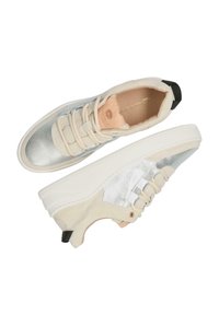 Sneaker bicolore con punta metallica argento e corpo in suede color crema. Le caratteristiche includono lacci elastici, tomaia testurizzata e suola in gomma bianca.