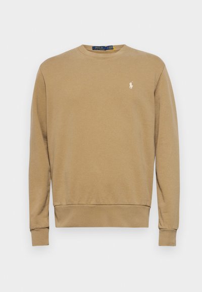 Φούτερ από ελαφρύ καφέ υλικό, με στρογγυλή λαιμόκοψη, μακρύ μανίκι, ριγωτές μανσέτες και στριφώρισμα στο τελείωμα. Διαθέτει μικρό λευκό λογότυπο στη αριστερή πλευρά του στήθους.