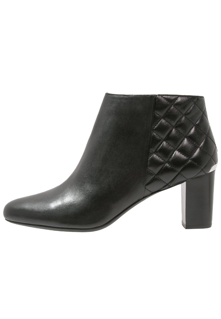 Bottines en cuir noir avec un bout pointu, un détail latéral matelassé et un talon épais, présentant une texture lisse et un design épuré.