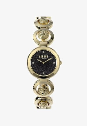 Reloj en tono dorado con un dial negro de patrón radial, acentos de cristal y eslabones circulares con motivos de cabezas de león detallados.