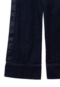 Ciemnoniebieskie dżinsy o prostym kroju, z teksturowanym wykończeniem i bocznymi paskami z wytłoczonym napisem "UNIWERSYTET" w kontrastującym kolorze.