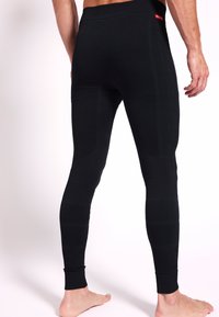 Leggings térmicos negros con un diseño texturizado, que presentan un ajuste ceñido y puños acanalados. Las costuras notables añaden estructura y estilo.