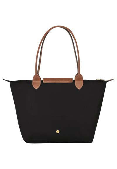 Black tote bag with brown leather accents, two handles, and a zip closure. Notable features include a gold button detail and fabric texture.