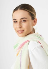 Foulard léger en crème avec des motifs chevrons colorés en rose, vert, violet et accents jaunes ; texture douce et design fluide.