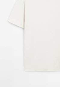 Krátký rukáv, jednobarevné off-white tričko na bílém pozadí, zobrazená levá strana s viditelným švem na rukávu a lemu.