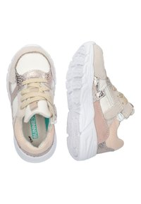 Zapatillas juveniles con una combinación de tonos beige, blanco y acentos metálicos. Un tejido texturizado y un cierre de cremallera complementan una suela flexible.