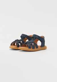 Mørkeblå lærsandaler med flere stropper og åpen design. Tan gummisåle, med et teksturert grep mønster. Justerbar stropp.