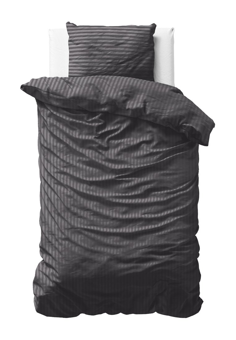 Letto singolo con cuscino a righe grigie scure e copripiumino spiegazzato su uno sfondo bianco, vista dall'alto.