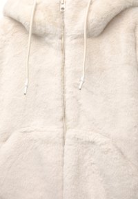 Giacca in fleece color crema con cappuccio, zip frontale e lacci. Presenta una texture morbida e due tasche frontali.