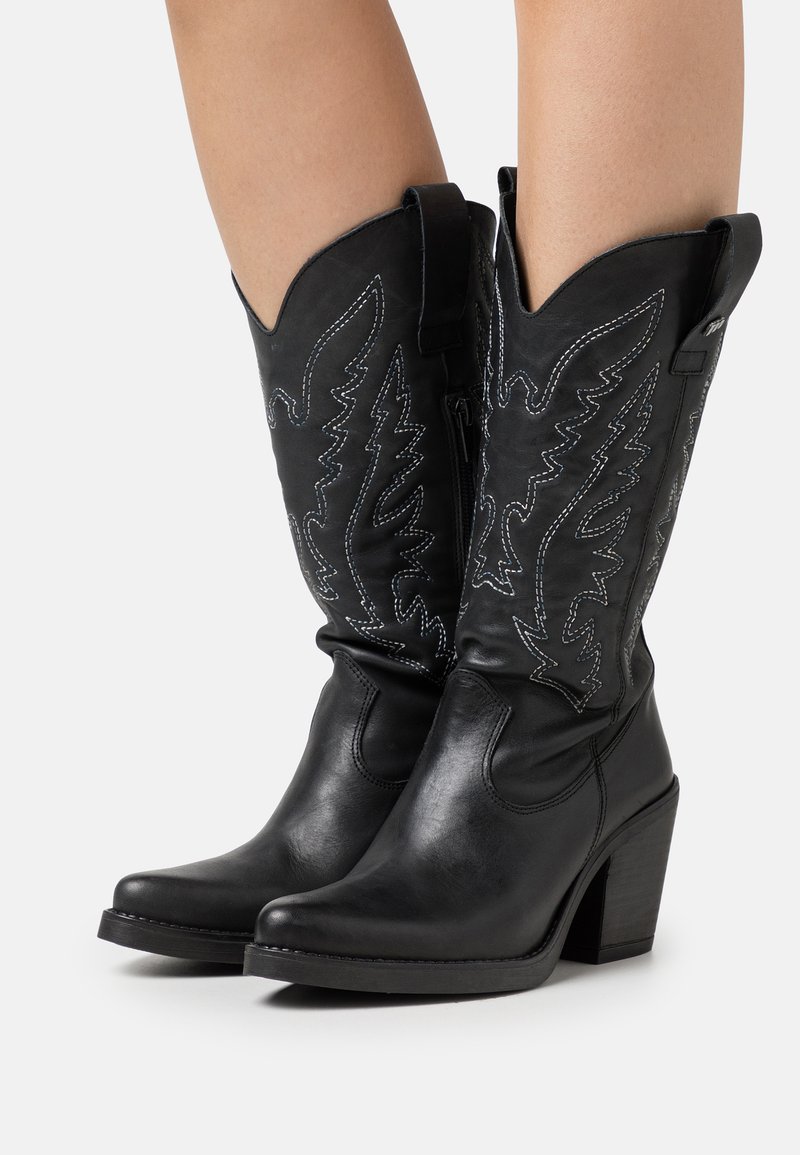 Bottes de cowboy en cuir noir avec des bouts pointus, des coutures décoratives et un talon de hauteur moyenne. Elles sont dotées de tirettes pour un enfilage facile.