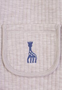 Tessuto beige chiaro con una texture a righe presenta un design ricamato di una giraffa blu su una tasca. I punti di cucitura sono ordinati e ben definiti.