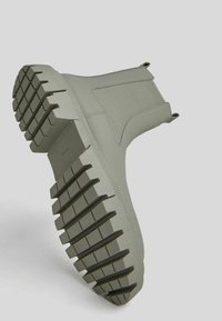 Szare botki za kostkę z fakturowanym wierzchem, kontrastującą masywną podeszwą oraz wyraźnym wzorem bieżnika. Zawierają pętelki ułatwiające zakładanie.