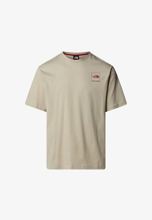 Beige katoenen t-shirt met korte mouwen. Heeft een klein rood logo grafisch op de linkerborst. Klassiek crewneck ontwerp.