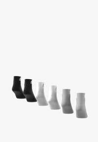Cinco pares de calcetines tobilleros en negro, blanco y gris. Cada calcetín cuenta con puños acanalados y un pequeño logo en el lado, mostrando un diseño minimalista.