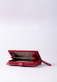 Red leather wallet with a zip closure, featuring multiple compartments and a patterned brown interior. Includes a wrist strap.