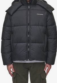 Black puffer jacket with a quilted design, front zipper, and logo detail. Features a high collar and side pockets. Material appears smooth.