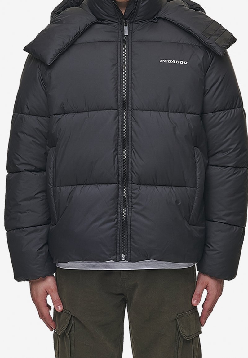 Black puffer jacket with a quilted design, front zipper, and logo detail. Features a high collar and side pockets. Material appears smooth.