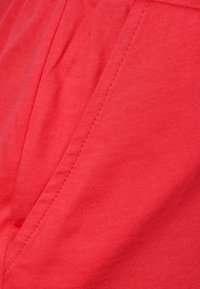 Tela roja con textura de acanalado fino, que muestra puntadas y costuras. El color es uniforme sin patrones o acentos visibles.