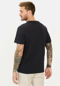 Navyblå kortærmet t-shirt i bomuld med rund halsudskæring og en afslappet pasform. Synlige tatoveringer på armene tilføjer detalje.