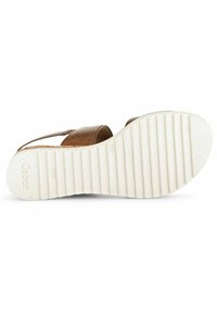 Sandale en cuir marron avec deux larges lanières, une semelle en caoutchouc blanc texturé et un petit talon. Présente le nom de la marque embossé sur la semelle.