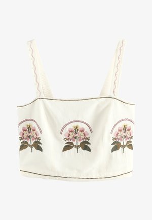 Hvid crop-top med brede skulderstropper, prydet med tre broderede lyserøde blomsterklaser og dekorative syninger langs kanterne.