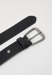 Cinto de couro preto com fivela de metal prateada, apresentando uma textura suave, bordas cosidas e um detalhe de logotipo próximo à fivela.