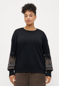 Μαύρη μπλούζα με μακριά μανίκια που διαθέτει περίπλοκα κεντήματα σε αποχρώσεις μπλε, πορτοκαλί και λευκού γύρω από τους μανικιού.