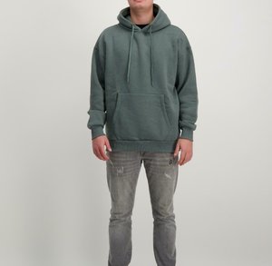 Groene hoodie met een trekkoordcapuchon, een voorste kangoeroezak en geribde manchetten. Draagt een versleten lichtgrijze spijkerbroek.