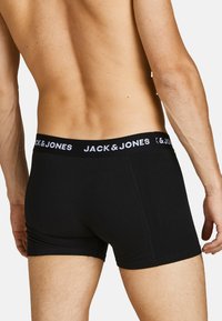 Schwarze Baumwoll-Boxershorts mit einem dicken elastischen Bund, der "JACK & JONES" in weißer Schrift zeigt; taillierte Passform, glatte Textur.
