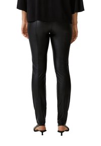 Svarta leggings i konstläder med smal passform, slät yta och sömdetaljer, kombinerade med svarta öppna klackar.